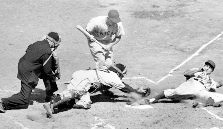 Chicago Cubs infielder Bob Ramazzotti, right, steals home safely under the tag of Pittsburgh catcher Phil Masi as batter Herman Reich and umpire Beans Reardon look on, in the third inning of a 9-5 Cubs road victory, Sept 13, 1949.