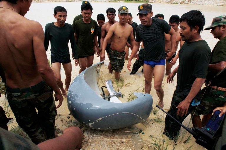 Rescue workers gather around a part of a crashed helicopter retrieved from a pond, a site of an helicopter crash in Prey Sar village at the outskirt of Phnom Penh, Cambodia, Monday, July 14, 2014. A Cambodian military helicopter crashed during a training mission south of the capital on Monday, killing five people on board, police said.(AP Photo/Heng Sinith)