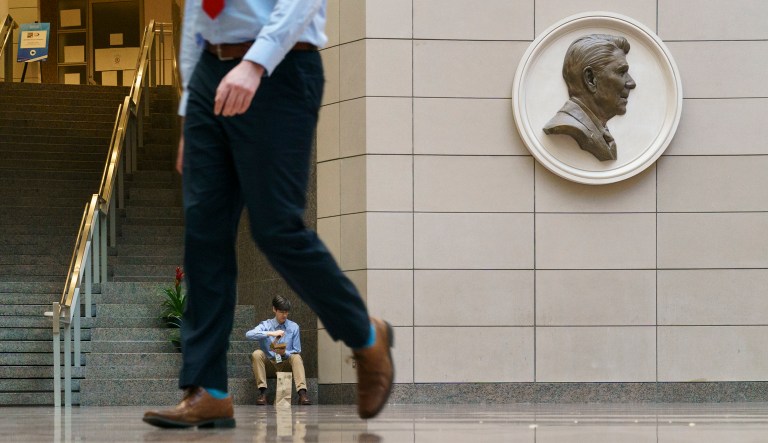Federal worker Chris Brinkerhoff eats his lunch in the atrium of the Ronald Reagan Building and International Trade Center in Washington, Monday, Jan. 28, 2019. An image of President Ronald Reagan hangs on the wall at right. Brinkerhoff was able to return to work today with the end of a partial government shutdown. The shutdown started in December over funding for President Donald Trump's promised U.S.-Mexico border wall. Trump on Friday agreed to end the shutdown for three weeks.