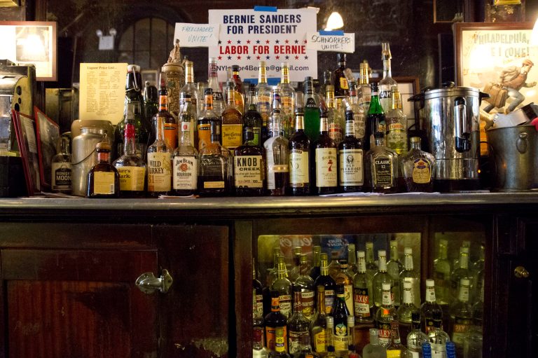A sign endorsing Democratic presidential candidate, Sen. Bernie Sanders, I-Vt., for president hangs behind the liquor bottles at the Old Town Bar, Tuesday, March 8, 2016, in New York. (AP Photo/Mary Altaffer)