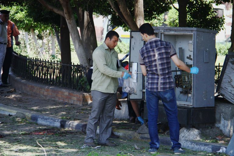 Egyptian investigators collect debris found at the site of a bomb blast that targeted a traffic police post in Cairo's Heliopolis suburb, Egypt, Friday, May 2, 2014. A bomb blast near a court building in Cairo killed at least one policeman and wounded a few others on Friday, shortly after two suicide bombers struck in Egypt's restive Sinai Peninsula in near-simultaneous attacks that killed at least one soldier and wounded several people. (AP Photo/Ahmed Gomaa)