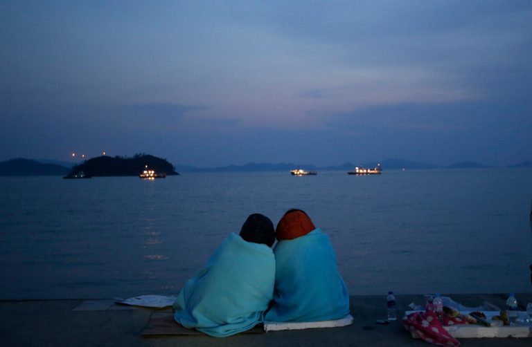Relatives of passengers aboard the sunken ferry Sewol sit near the sea at a port in Jindo, south of Seoul, South Korea, Sunday, April 20, 2014. After more than three days of frustration and failure, divers on Sunday finally found a way into the submerged ferry off South Korea's southern shore, discovering more than a dozen bodies inside the ship and pushing the confirmed death toll to over four dozens, officials said. (AP Photo/Lee Jin-man)
