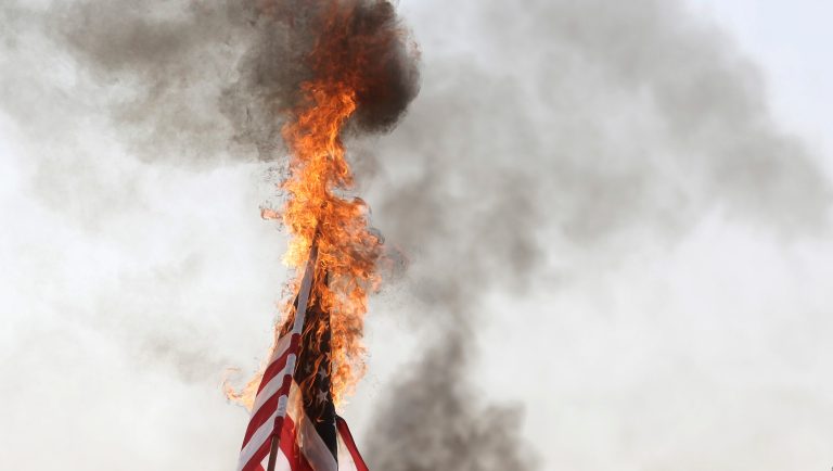 Palestinian protesters burn an American flag during a protest at the Gaza Strip's border with Israel, Friday, April 6, 2018.