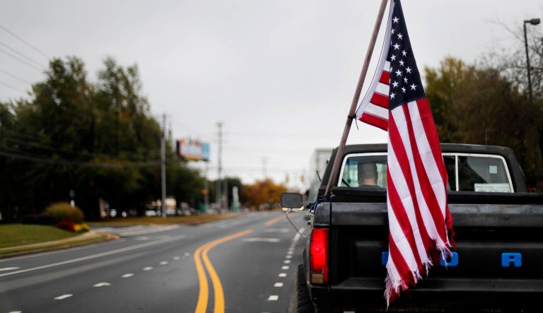 An American flag hangs on the back of a pickup truck on election day as a motorist drives through Woodstock, Ga., Tuesday, Nov. 6, 2018.