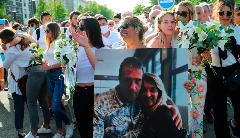 VÃ©ronique Monguillot, wife of Philippe Monguillot, bus driver life-threatening condition, waves people as she holds a picture of them during a white march in Bayonne, southwestern France, July 8, 2020, to protest against a bus driver attack in Bayonne on Sunday night. The bus driver is in life-threatening condition after being attacked by passengers who were barred from boarding his vehicle. 