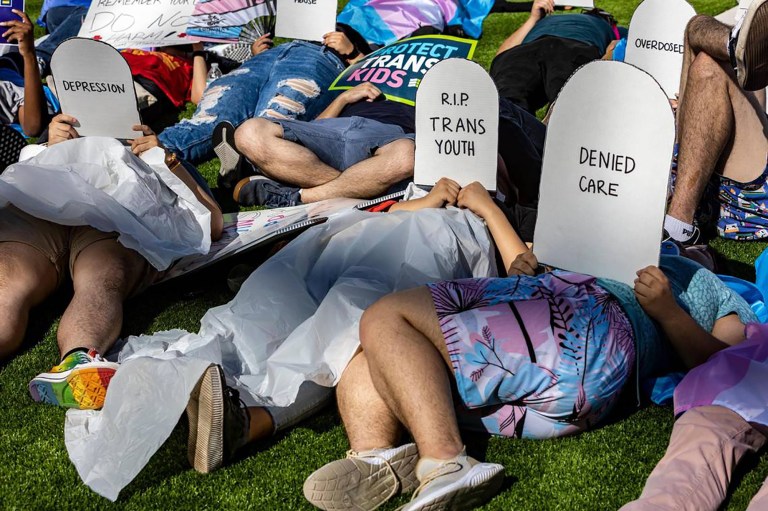 Protesters lie on the ground in front of the Marriott Fort Lauderdale Airport as the Florida Board of Medicine meets inside on Aug. 5. On the agenda was a discussion about a proposed rule to ban doctors from performing gender-affirming surgeries or providing puberty blockers to transgender minors. 