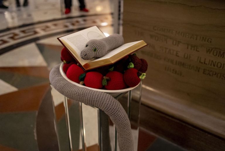 A crocheted snake and apples and a book by Copernicus on Dec. 6, 2022, make up the seasonal display placed by members of the Satanic Temple of Illinois at the Illinois State Capitol.