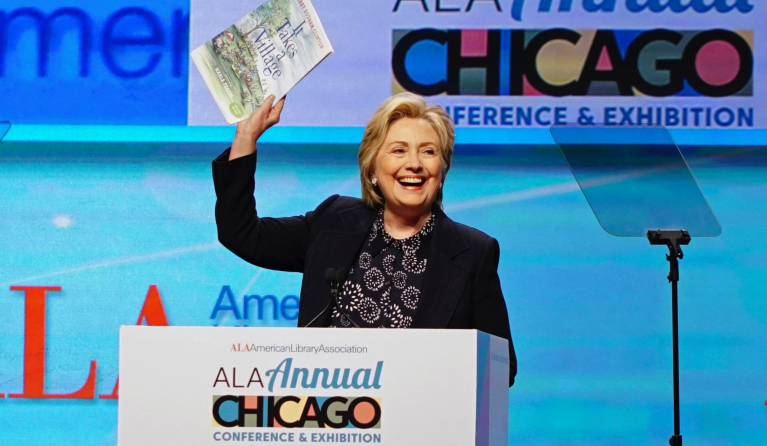 Hillary Clinton holds up an illustrated children's version of her book, 'It Takes a Village', as she speaks at the American Library Association (ALA) Annual Conference and Exhibition, Tuesday, June 27, 2017, in Chicago. (AP Photo/Teresa Crawford)