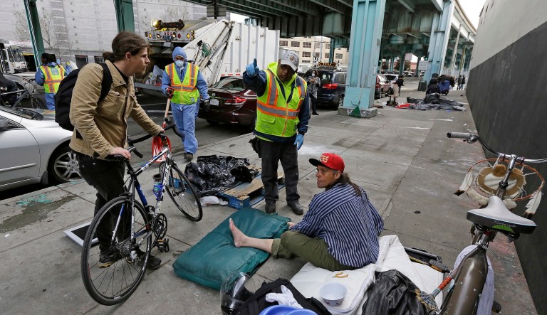 In this Feb. 26, 2016, photo, a San Francisco city worker tells a homeless man that the area next to him is about to be washed and points to an area he might want to move to.