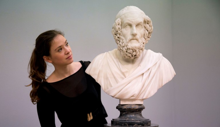 A Sotheby's auction house employee poses for photographs with the Francis Harwood marble bust of the ancient Greek poet Homer at their premises in London, Friday, Nov. 28, 2014.