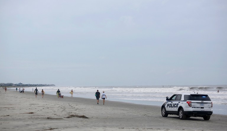 An Isle of Palms police car drives down the beach early morning on the Isle of Palms, S.C., as Hurricane Florence spins out in the Atlantic ocean Thursday, Sept. 13, 2018.