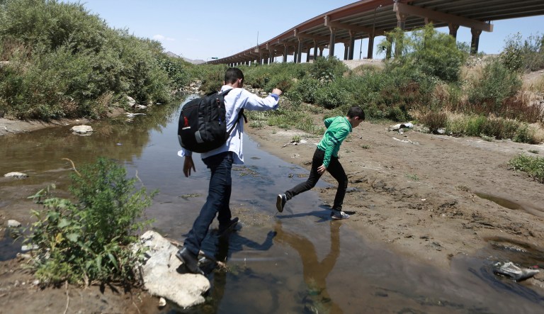 FILE - In this June 7, 2019 file photo, people cross the Rio Grande into the United States to turn themselves over to authorities and ask for asylum, as seen from Ciudad Juarez, Chihuahua, Mexico.
