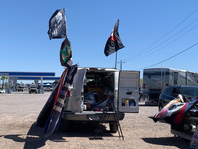 Tim Micklin sells thick woolen blankets and large specialty flags out of the back of a white van in Gila Bend, Arizona