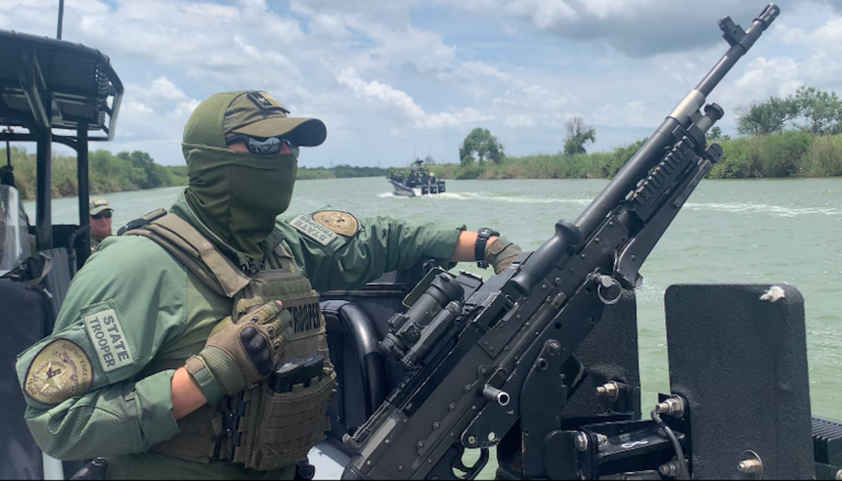 A Texas Department of Public Safety officer looks out toward the Mexico shoreline from the Rio Grande River.