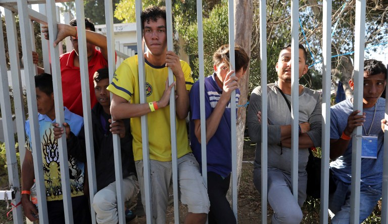 Central American migrants peer out from a migrant shelter in Tijuana, Mexico, Sunday, Nov. 18, 2018.