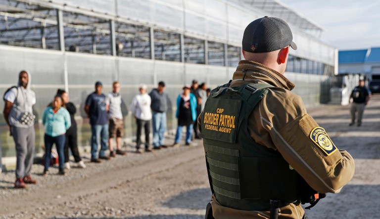 FILE â In this June 5, 2018, file photo, government agents stand guard alongside suspects taken into custody during an immigration sting at Corso's Flower and Garden Center in Castalia, Ohio.
