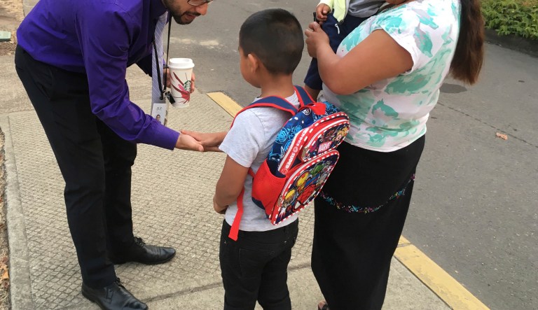 Oscar Belanger, assistant principal of Nellie Muir Elementary School, in Woodburn, Ore., where 82 percent of students are Latino, slaps five with a student arriving for the first day of class on Tuesday, Sept. 5, 2017.