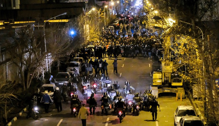 In this photograph taken Saturday, Jan. 11, 2020, Iranian police officers take position while protesters gather in front of Amir Kabir University in Tehran, Iran, to remember victims of a Ukrainian airplane shot down by an Iranian missile. On Monday, Jan. 13, 2020, online videos purported to show that Iranian security forces fired both live ammunition and tear gas to disperse demonstrators protesting against the Islamic Republic's initial denial that it shot down a Ukrainian jetliner.