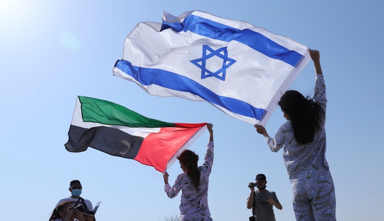 Israeli model May Tager, right, holds Israel's blue-and-white flag bearing the Star of David while next to her Anastasia Bandarenka, a Dubai-based model originally from Russia, waves the Emirati flag, during a photo shoot in Dubai, United Arab Emirates, Sunday, Sept. 8, 2020.