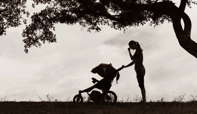A mother pushes a stroller while under emotional stress.
