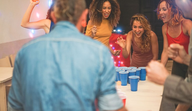 Young people playing beer pong at a party.
