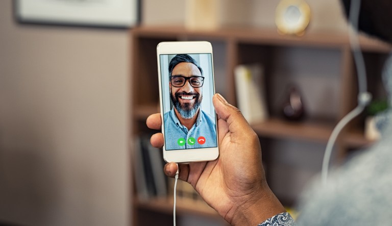 Closeup hands of man holding smartphone doing video calling with friend. 