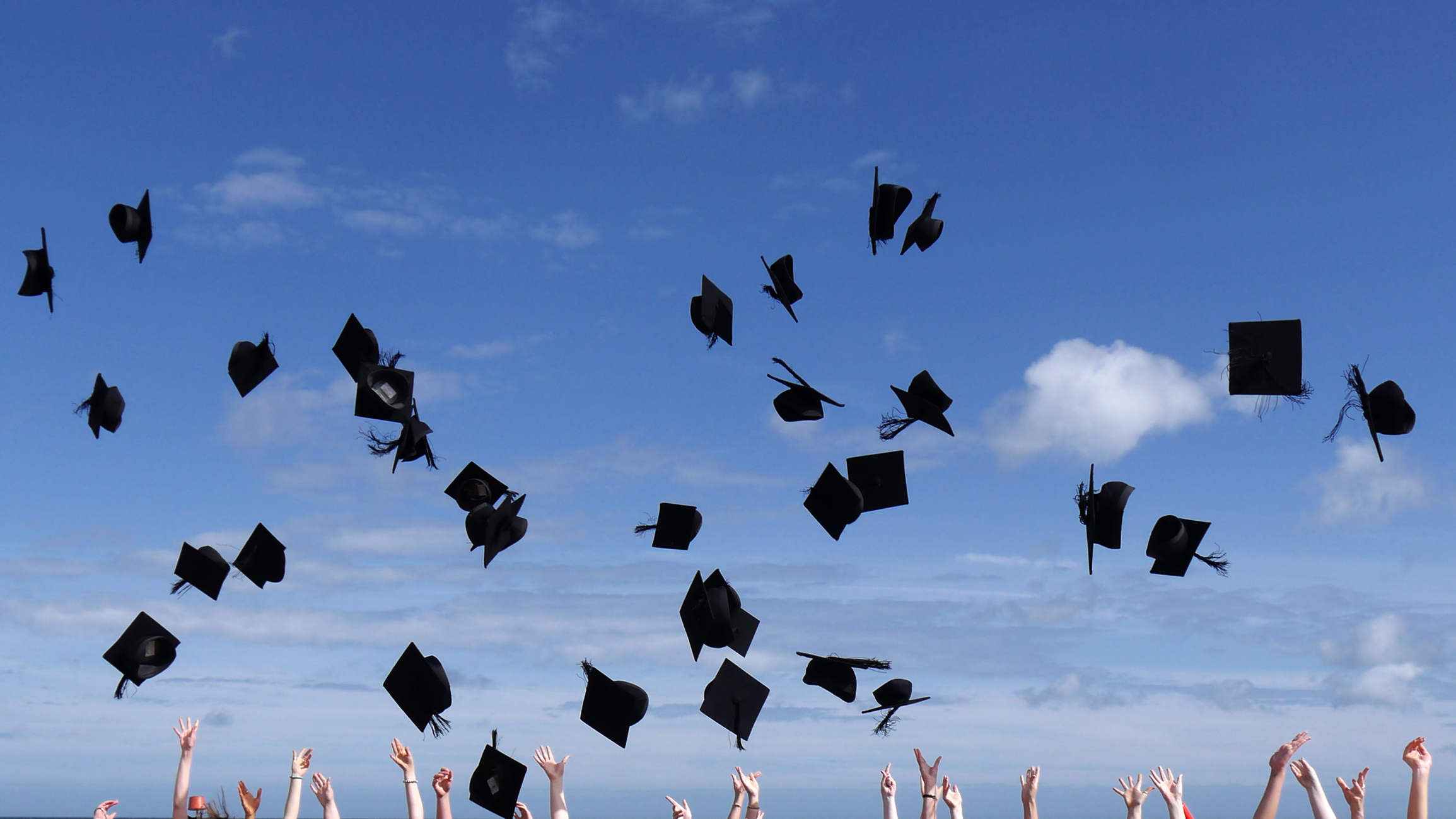Graduation celebrations, throwing caps into a blue sky