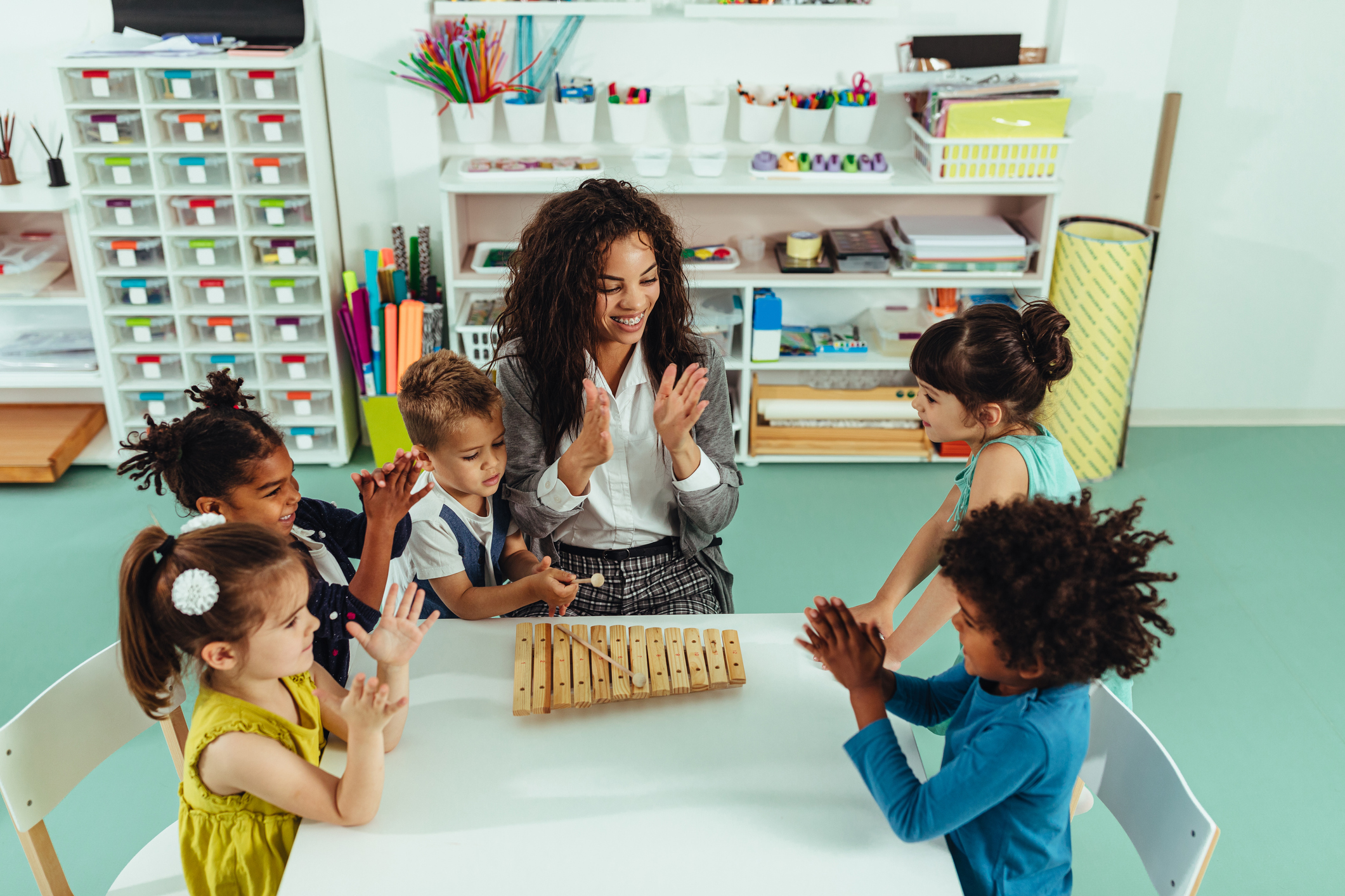 Teacher helping young preschool kids playing musical toys