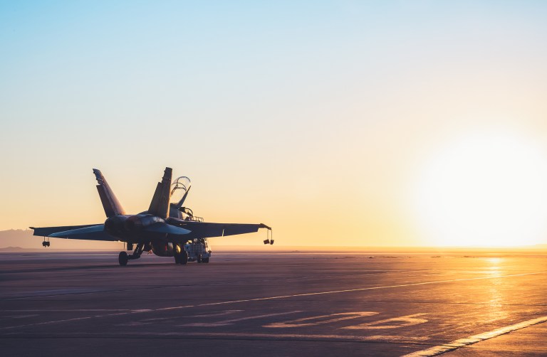 Jet fighter on an aircraft carrier deck against beautiful sunset sky. Elements of this image furnished by NASA.