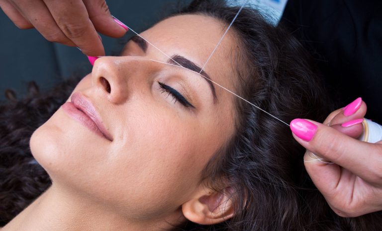 A woman in a beauty salon having her eyebrows threaded.