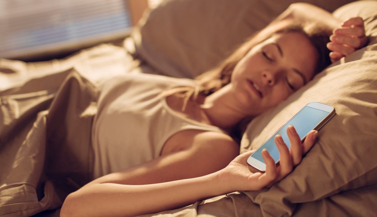 Close up of a young woman  fall asleep next to smart phone-sleeping