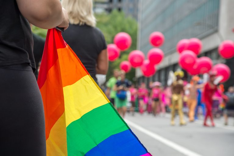 Gay rainbow flags at gay pride parade with blurred spectators in the background