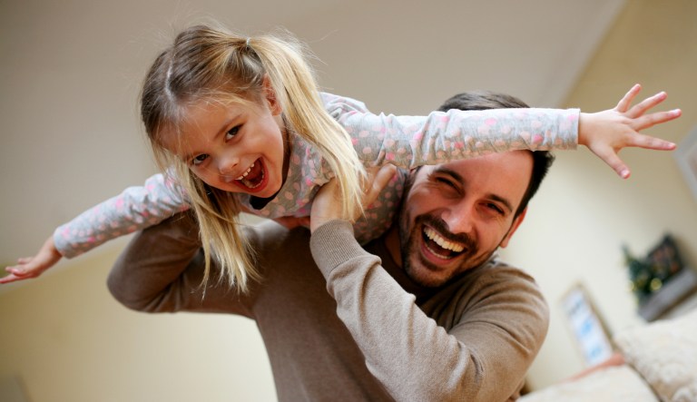 A daughter goes on a piggyback ride with her dad.