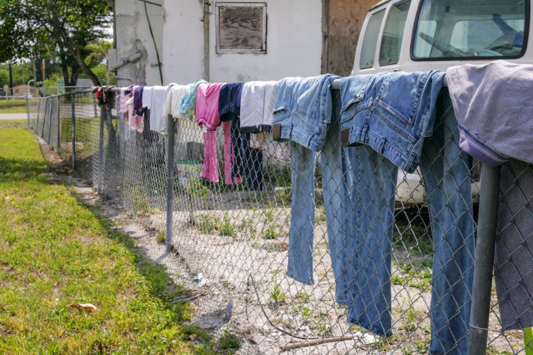 Work and Children's clothes are hung outside on a chain link fence in Florida.