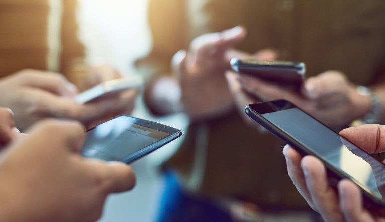 A group of people check their smartphones.