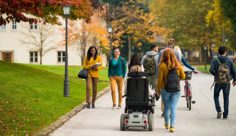 Students walk through a green area.