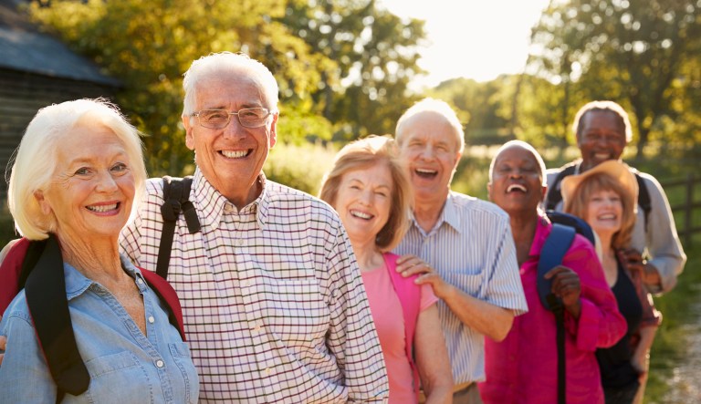 Elderly hikers stand outside of a farm.