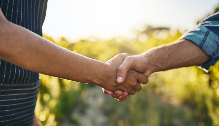 A man and woman shake hands on a farm.