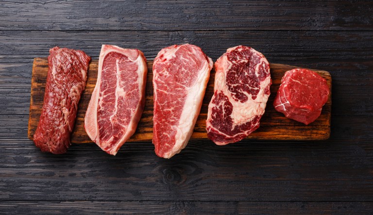 Variety of raw black Angus prime meat steaks Machete, Blade on bone, Striploin, Rib eye, Tenderloin fillet mignon on wooden board.
