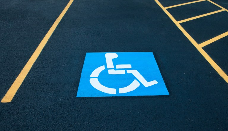 Disabled blue parking sign painted on dark asphalt with yellow lines.