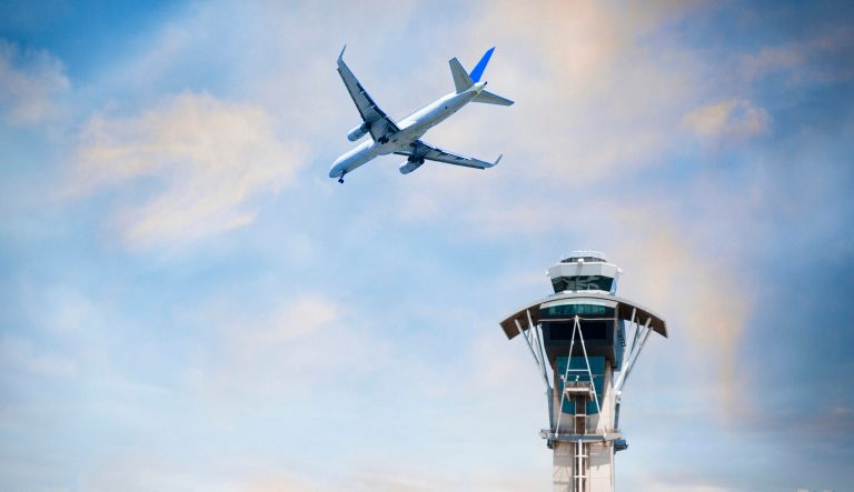An airplane flies over an air traffic control tower at LAX in California.