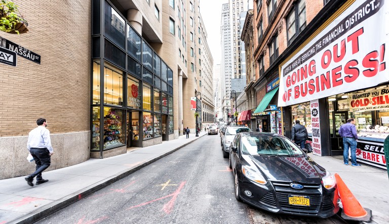 In this Oct. 30, 2017, photo, people walk on Nassau Street St. in New York City's Manhattan lower financial district, with a "Going Out of Business" sign at a store.