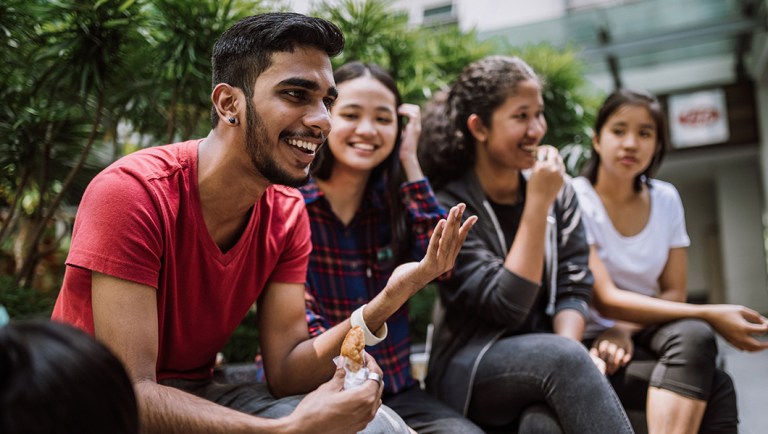 A group of college students chats over lunch.