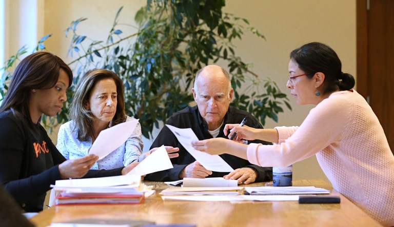 California Gov. Jerry Brown reviews a measure with his wife, Anne Gust Brown, second from left and staff Camille Wagner, left, Graciela Castillo-Krings, right, at his Capitol office, Sunday, Sept. 30, 2018, in Sacramento, Calif. Sunday is the last day for Brown to approve or veto bills passed by the legislature. Brown, who will be leaving office in January, is acting on some on the last pieces of legislation in his tenure as governor.
