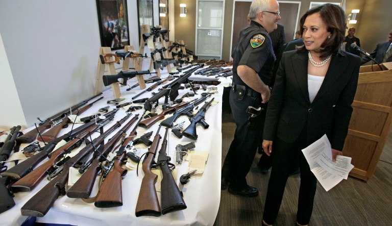 FILE - In this June 16, 2011 file photo, Attorney General Kamala Harris looks over some of the guns seized  from individuals legally barred from possessing them following a news conference in Sacramento,  Calif.