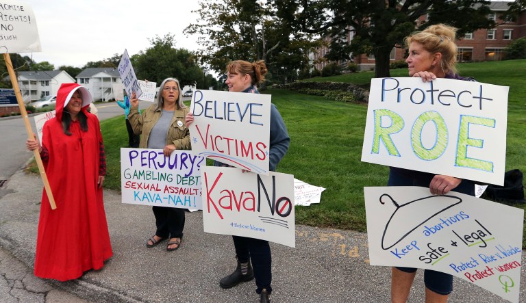 Demonstrators hold signs outside Saint Anselm College, Friday, Sept. 21, 2018, in Manchester, N.H., where U.S. Sen. Susan Collins, R-Maine, considered one of the few possible Republican "no" votes on Supreme Court nominee Brett Kavanaugh, is scheduled to speak. 
