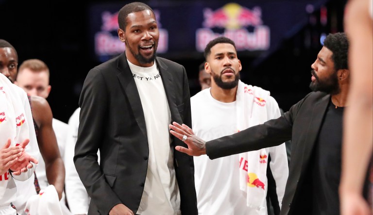 Injured Brooklyn Nets guard Kyrie Irving, right, puts his hand on fellow injured player Kevin Durant who smiles as he stands to greet teammates returning to the bench during a timeout in the second half of an NBA basketball game against the New York Knicks, Thursday, Dec. 26, 2019, in New York.