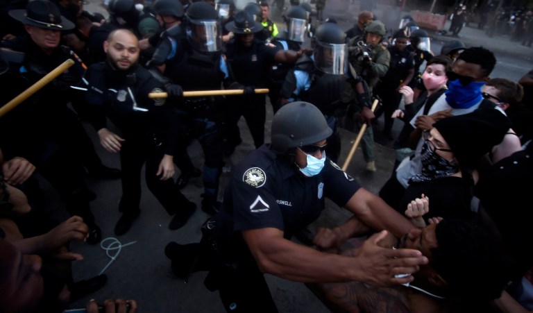 Police officers and protesters clash near CNN Center, Friday, May 29, 2020, in Atlanta, in response to George Floyd's death in police custody in Minneapolis on Memorial Day. The protest started peacefully earlier in the day before demonstrators clashed with police. 