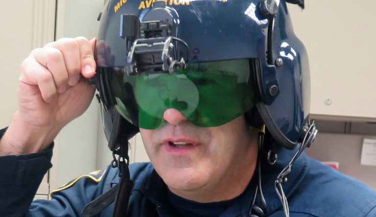 In a March 14, 2017 photo, Michigan State Police pilot Jerry King, shows a anti-laser shield in his office at a state police facility at Capital Region International Airport, in Lansing, Mich. Pilots use the anti-laser shield on their helmet when they are trying to pinpoint the source of a laser that is being shined at them or other aircraft. Michigan is poised to join a growing list of states and enact its own stiff law that criminalizes increasingly frequent laser attacks that are endangering pilots and their passengers.