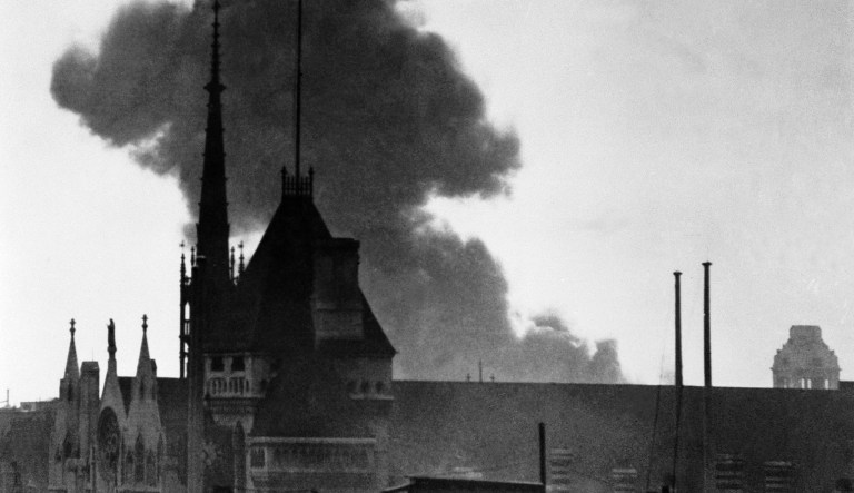 In this view from a Fleet Street rooftop, a cloud of smoke rises after a German buzz bomb exploded in a side street off Drury Lane, behind the towers of the law courts building in Central London, in June 1944. The Daily Herald building and other structures were blasted.